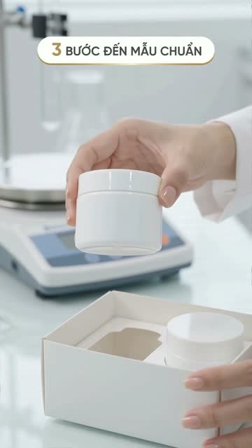 Bàn tay đặt hũ kem trắng vào hộp đựng mẫu trên bàn lab, cạnh cân điện tử, trên hình có dòng chữ "3 bước đến mẫu chuẩn"