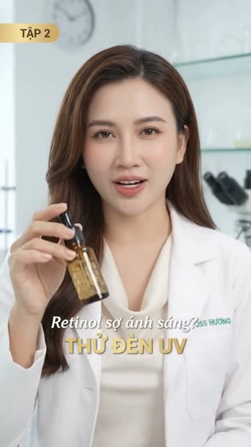 Chị Hương mặc áo blouse trắng cầm lọ serum thủy tinh màu hổ phách có ống nhỏ giọt, phía sau là kính hiển vi; góc trái ghi "Tập 2", chữ trên hình: "Retinol sợ ánh sáng? Thử đèn UV"
